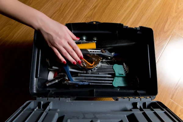 Girl with red manicure reaches for the tools in the tool box — Stock Photo, Image