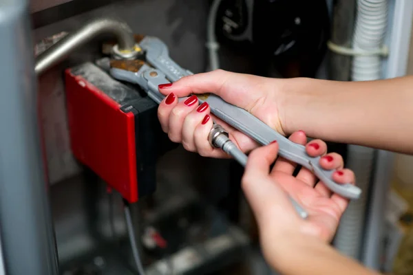 Жіночі руки роблять чоловічу важку роботу по ремонту газового котла — стокове фото