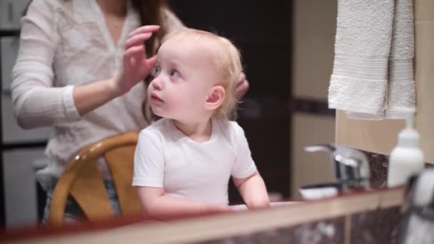 Kleines Mädchen Sieht Sich Selbst Badezimmerspiegel Während Mama Ihre Haare — Stockvideo