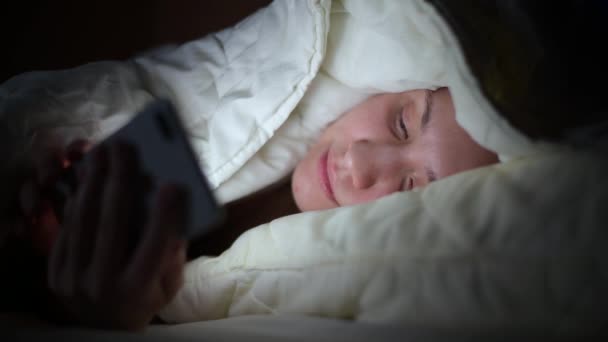 由于失眠 静坐等原因 这个女孩夜间躺在被窝里 用智能手机穿过新闻网 — 图库视频影像