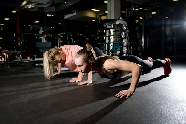 Två flickvänner gör armhävningar i gymmet. — Stockfoto