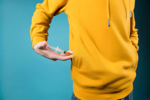 Adolescente muestra una jeringa con una droga, sacándola del bolsillo de una sudadera . — Foto de Stock