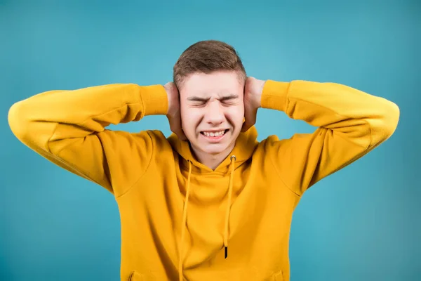 Joven se sujeta la cabeza y las orejas con las manos, entrecerrando los ojos — Foto de Stock