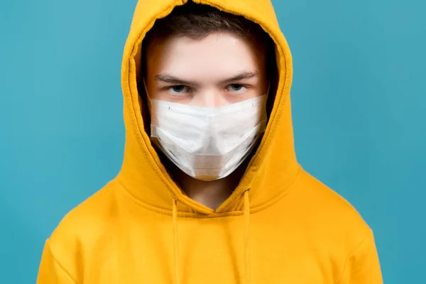 A young guy with a medical mask on his face looks straight ahead. close-up — ストック写真