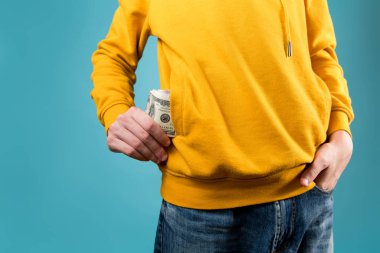 Genç adam sarı bir kazağın cebine para koyar ya da çıkarır.