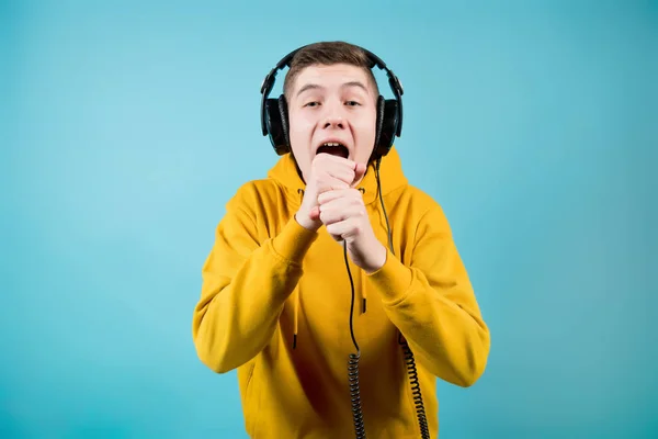 Een man in heldere kleren en grote koptelefoon schreeuwt in een denkbeeldige microfoon — Stockfoto