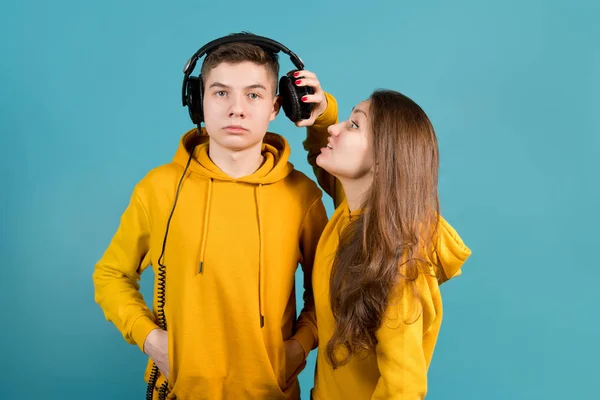 the girl pushes one earphone away from the guy in order to tell him something in the ear