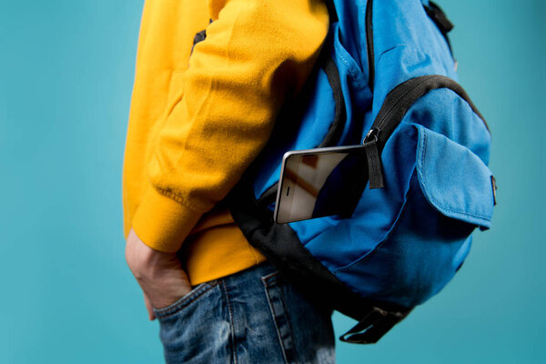 smartphone sticks out of a teenager's backpack