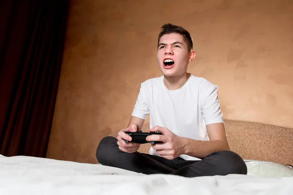 Jovem cara emocionalmente joga um jogo de computador com o joystick — Fotografia de Stock
