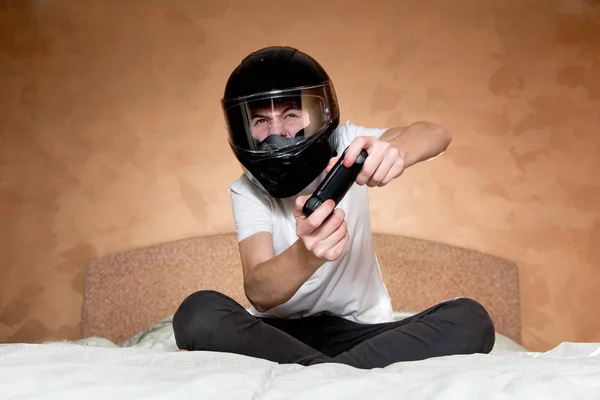 Хлопець у шоломі мотоцикла занурений у відеогру. — стокове фото