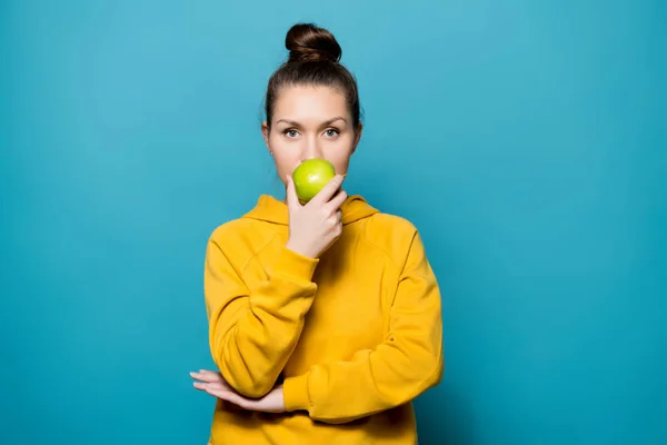 Kalm meisje in een sweatshirt ruikt een frisse groene appel — Stockfoto