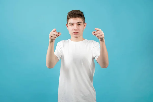 Jovem em uma camiseta branca mostra com os dedos indicadores para a câmera e faz um rosto confiante — Fotografia de Stock