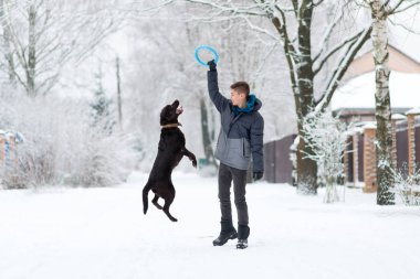 Bir çocuk kışın bir köpekle köyde yürür ve oynar.