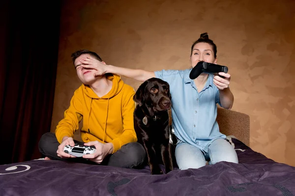 Uma menina aplica um truque em um jogo com um cara, um cão se senta ao lado deles . — Fotografia de Stock