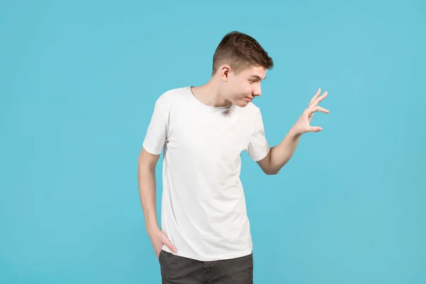 Young boy in a white T-shirt cunningly holds out his hand to the side as if taking invisible gifts — 스톡 사진