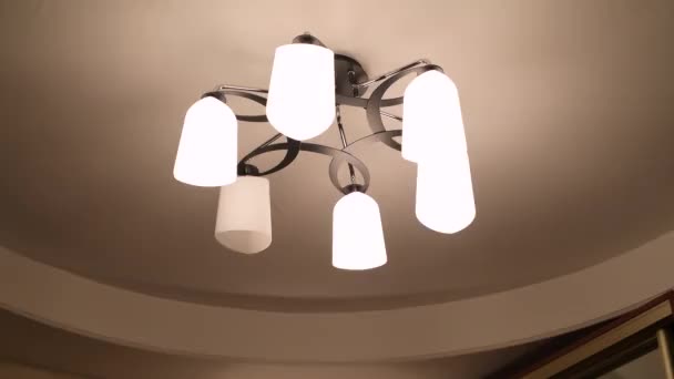 Girl changes a burned out lamp in a chandelier — Stock Video