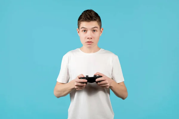 Adolescente bonito com um joystick em mãos em um fundo azul — Fotografia de Stock