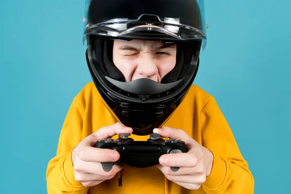 Um adolescente em um capacete de motocicleta com um joystick de um console de jogo pisca — Fotografia de Stock