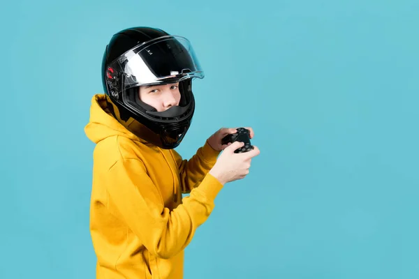 Um jovem em um capacete de motocicleta com um joystick de um console de jogo — Fotografia de Stock