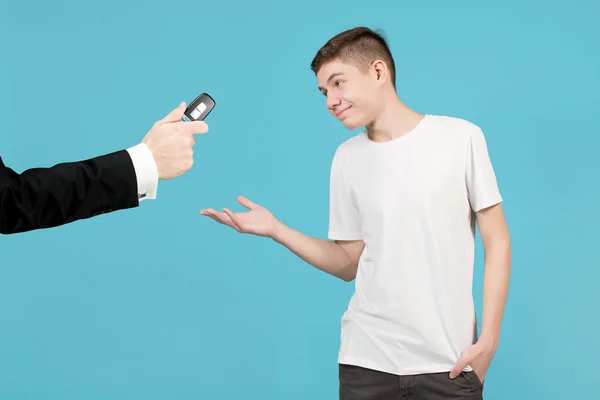 Adolescente alegremente aceita uma chave de carro, que um homem de jaqueta lhe reserva — Fotografia de Stock
