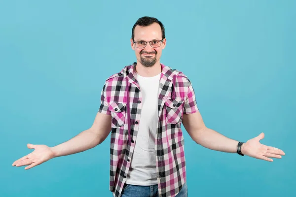 Junger Mann mit Brille und kariertem Hemd lächelt und breitet seine Handflächen seitlich aus — Stockfoto