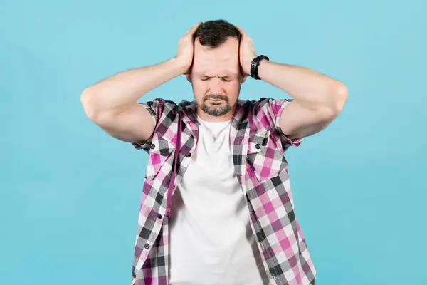 Hombre con rastrojo aprieta su cabeza con sus manos debido al dolor — Foto de Stock