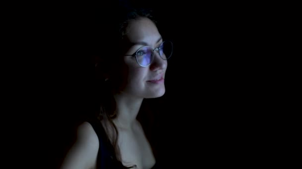 Mujer sonriente en gafas camina hacia la ventana, abre la cortina y mira hacia fuera . — Vídeos de Stock