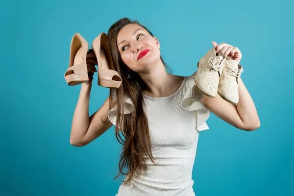 Das Mädchen hält hochhackige Schuhe und lässige leichte Schuhe in den Händen. — Stockfoto