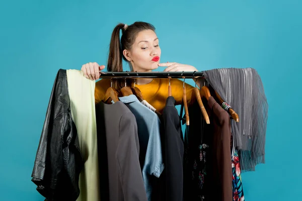 Frau in heller Kleidung guckt hinter einem Kleiderbügel hervor und entscheidet, was sie anzieht — Stockfoto