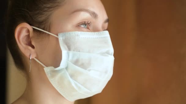 Närbild Ung Kvinna Skyddande Medicinsk Mask Tittar Hon Genom Fönstret — Stockvideo