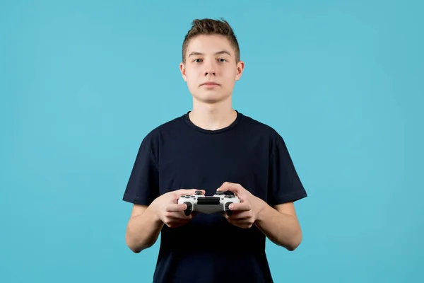 Lindo adolescente con un joystick en las manos sobre un fondo azul — Foto de Stock