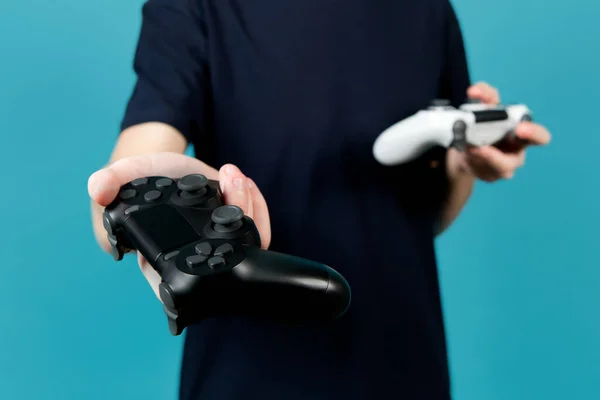 Um adolescente segura um joystick preto, segurando em suas mãos um joystick branco também — Fotografia de Stock