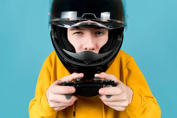 Close-up de um adolescente em um capacete de motocicleta preto e com um joystick em suas mãos — Fotografia de Stock