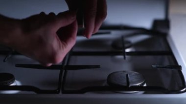 Bir adam gaz sobasını kibritle yakar, yakın plan. Gaz ateşlemesi