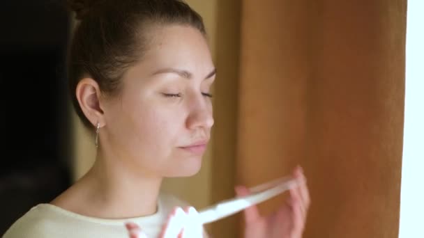 Close-up de uma jovem mulher que usa uma máscara médica protetora e olha para fora — Vídeo de Stock