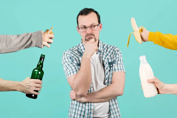 L'homme fait face à un choix - boire de l'alcool et de la fumée, ou boire du lait et manger une banane — Photo