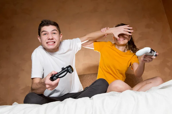 The guy prevents the girl from looking at the screen to defeat her in the game — Stock Photo, Image
