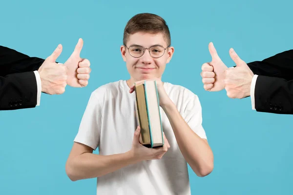 Um nerd com óculos sorri, franzindo os lábios e segurando livros para si mesmo . — Fotografia de Stock