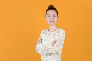 Kız kollarını kavuşturdu ve gururla dik baktı. Turuncu-sarı arka planda izole edilmiş