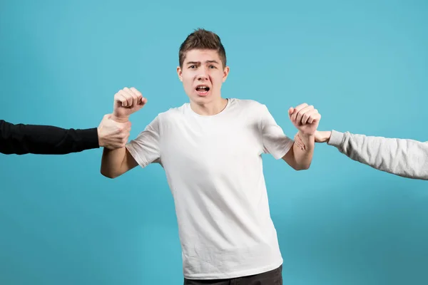 O cara está puxando por mãos em direções diferentes, o adolescente está chocado e confuso — Fotografia de Stock