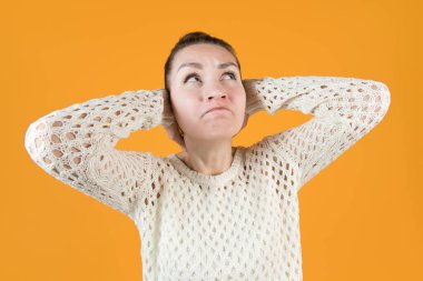 Genç kadın kulaklarını sıkıca kapatır ve öfkeyle yukarı bakar. Geniş açı