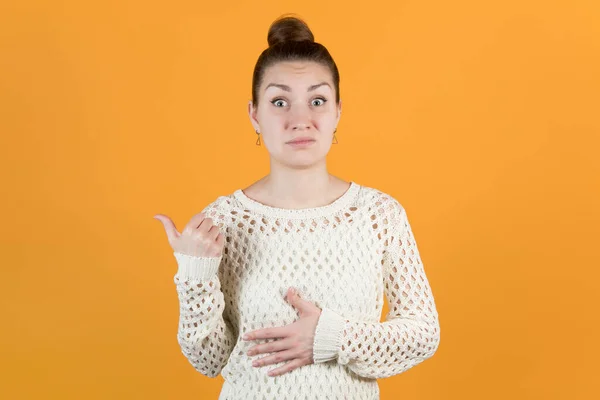 Girl shows thumb to the side and expresses surprise with horror in her face — Stock Photo, Image
