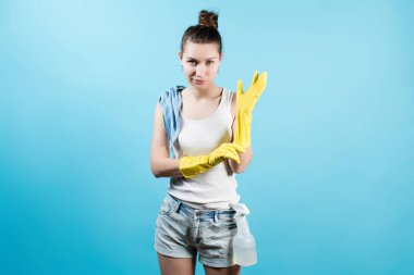 Sırıtan genç bir kadın eline koruyucu sarı bir eldiven takıyor. Kadın temizlik için hazırlanıyor.