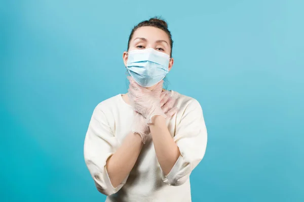 保護医療マスクの若い女性は状況が彼女を窒息させていることを彼女の手で示す 青に隔離された — ストック写真