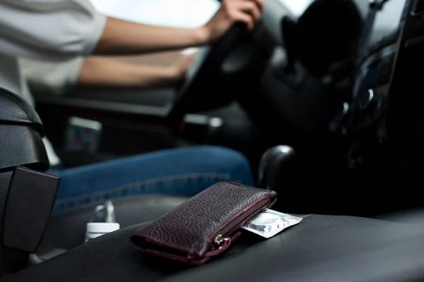 A condom sticks out of the wallet next to the girl who is going on a date. Condom in a car in the seat next to the girl who drives the car