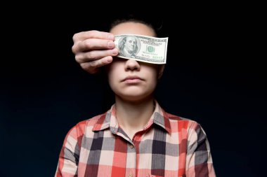 Yüz dolarlık banknotla kadın gözlerini kapat. Para karşılığı sessizlik satın almak. Şantaj ve yolsuzluk. Koyu arkaplan