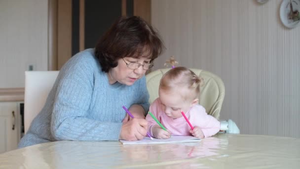 Ein kleines Mädchen sieht zu, wie ein Kindermädchen ein Album zeichnet. Ein Kind lernt zeichnen — Stockvideo