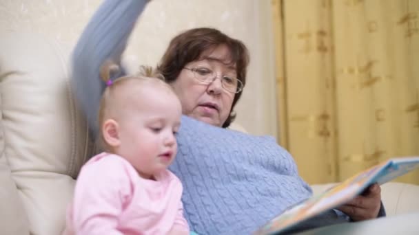 Γιαγιά δείχνει εγγονή ένα παιδικό βιβλίο, επιλεκτική εστίαση στη γυναίκα — Αρχείο Βίντεο