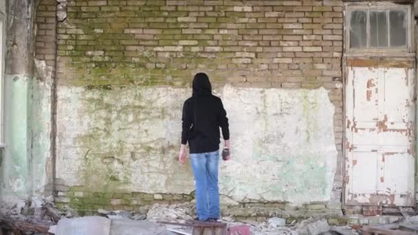 En tonåring målar på en vägg med en sprayburk — Stockvideo