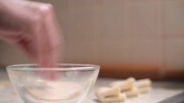 Genç bir kadın ellerinde şekerle kurabiye heykeli yapıp daha sonra fırında pişiriyor.